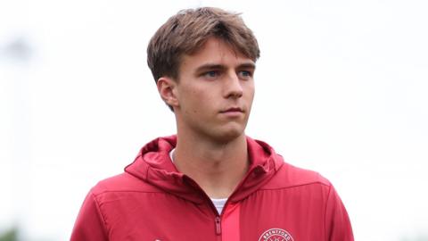 Julian Eyestone stares into the distance wearing a red Brentford training top.