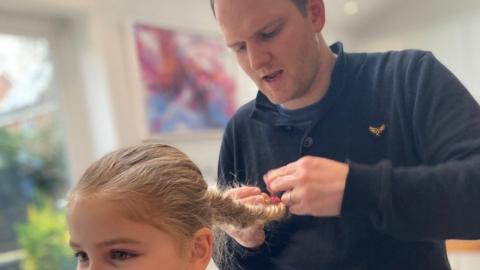 John Hardern plaiting his daughter's hair
