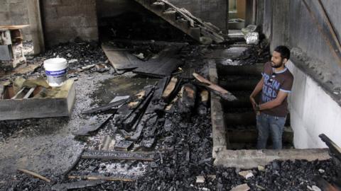 A man assesses damage to burned home in Digana, in Kandy on March 7