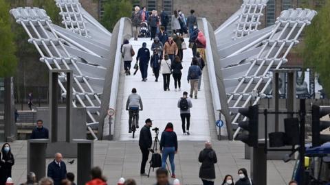 Pedestrians walk over the Millennium Bridge in London