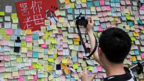 A man taking photographs of artwork and messages in support of protesters opposed to a China extradition law
