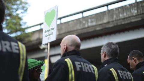 Firefighters with a United for Grenfell placard