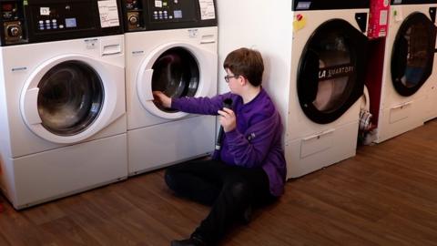 12-year-old sits and watches washing machines