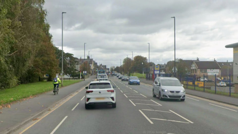 A busy A road with a cyclist on the pavement to the left