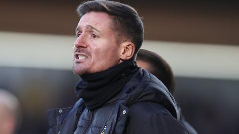 Barry Corr watches Cambridge United from the dugout