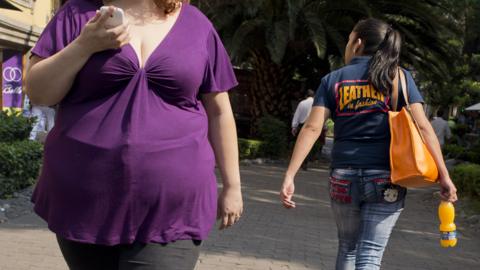 Obese woman, and woman holding soft drink, Mexico