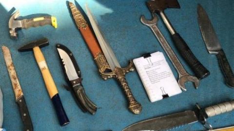 Weapons including sword, hammers and an axe laid out on a table