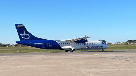 A Blue Islands plane on the tarmac at an airport. The plane is blue and white.
