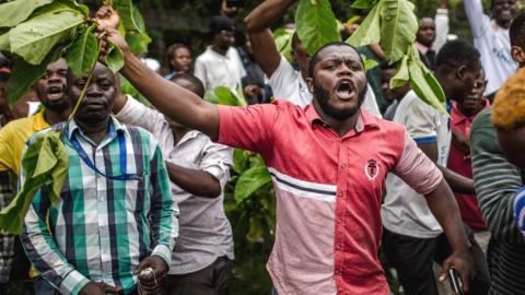 Protesters waiting to cast their ballot, demonstrate outisde the College St Raphael polling station, in Kinshasa, on December 30, 2018