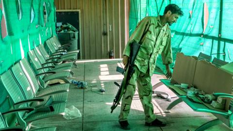 An Afghan army soldier surveys belongings left by the US military inside the Bagram Air Base, some 50 kilometers north of the capital Kabul.