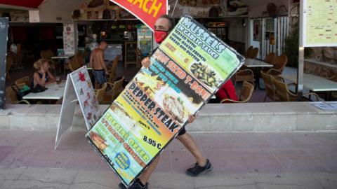 A waiter carries a sign in Magaluf