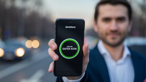 Tudor Cobalas holding phone showing SafeDrive app