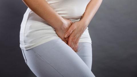 Stock image of a clothed woman holding her crotch area