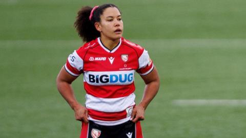Tatyana Heard standing on the pitch during a match for Gloucester-Hartpury holding her shorts