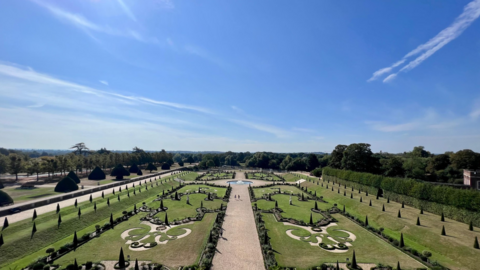 Picture of the gardens of Hampton Court in London with blue skies overhead.
