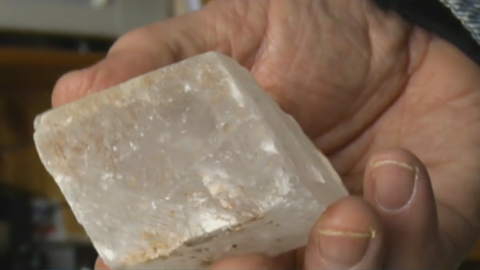 A hand holding a large square-shaped crystal