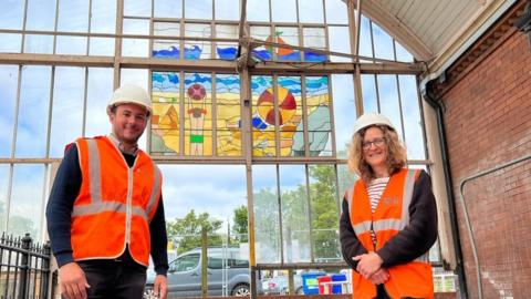 Stained glass artist Cate Watkinson and Nexus Project Manager Simon Manley next to the canopy and stained glass art work at Monkseaton Metro station