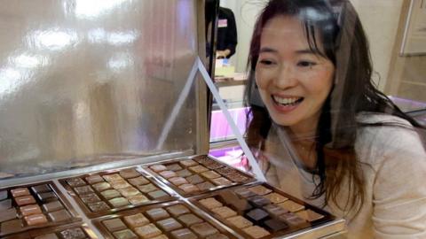 A woman looks at a tray of chocolates