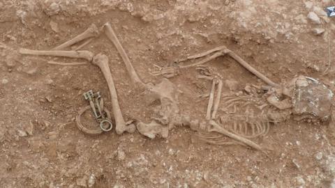 Skeleton of a woman buried in the ground with jewellery