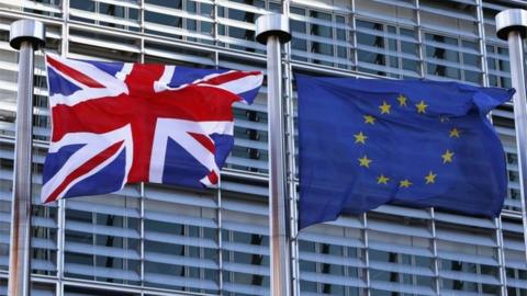 A Union Jack flag flutters next to European Union flags