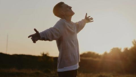 Image of Nathan Evans. He is pictured with his arms out, looking up to the sky.