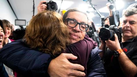 Jens Söring, who served 33 years in prison for a double murder, is hugged by a supporter as he arrives for a press conference in Germany, 17 December 2019