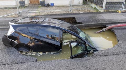 Car in sinkhole submerged in water