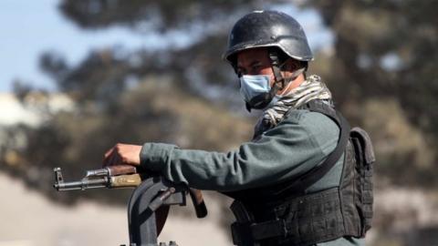 An Afghan security official stands guard on a road side check point in Herat, Afghanistan