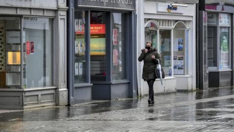 Woman walking past shops in Bridgend
