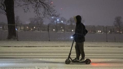 A person riding an e-scooter in the snow