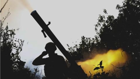 A Ukrainian soldier uses a grenade launcher in the direction of Avdiivka at the frontline in Donbas