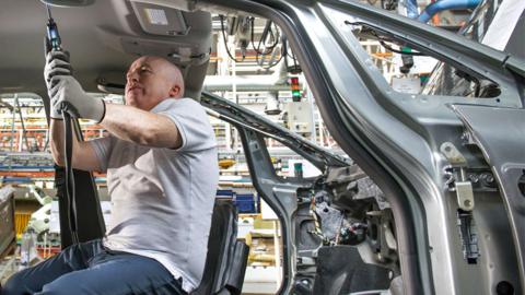 Stock image of a worker in a car factory