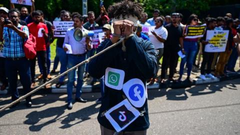 A blindfolded activist with a rope tied around his wrists