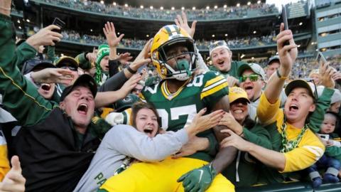 Romeo Doubs celebrates with Green Bay Packers fans after scoring a touchdown