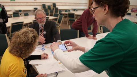 A precinct worker documents the process with her phone as Iowa Caucus precinct workers count paper ballots