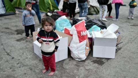 A girl stands next to cardboard boxes and plastic bags at the port of Piraeus near Athens where thousands of stranded refugees and migrants have found a temporary shelter on 15 March 2016.