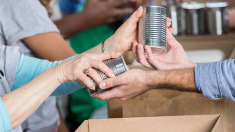 handing over tins at a food bank