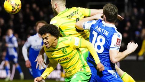 Norwich's Sam McCallum (left) and Ben Gibson battle with Bristol Rovers' Chris Martin