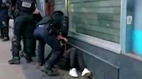 A French police officer punches a man while he is being detained during yellow vest protests in Paris, 18 January 2020