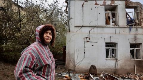 A woman stands near a destroyed building in the city of Kupiansk, north-eastern Ukraine. Photo: April 2023