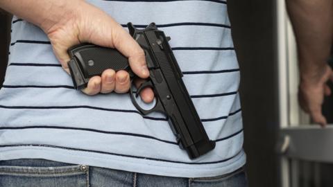 A man holding a gun behind his back