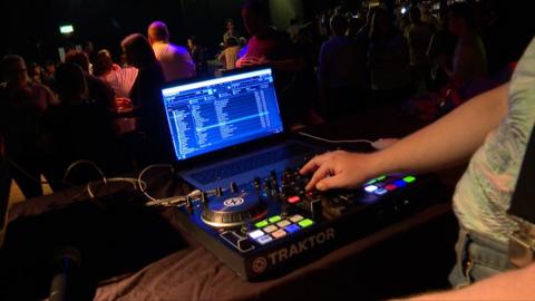 young DJ on the decks as people dance at the Black Box