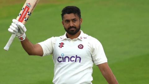 Karun Nair raising his bat in celebration of a century for Northamptonshire