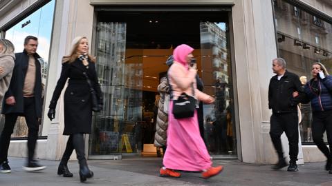 A woman is seen with other shoppers outside a Zara store in London in December
