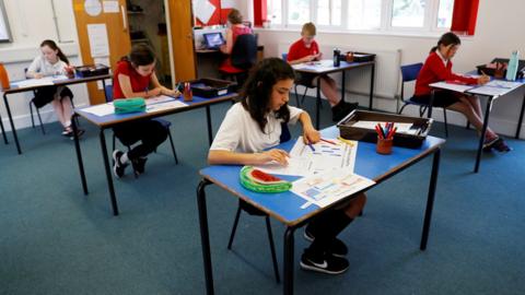 School children observing social distancing in class