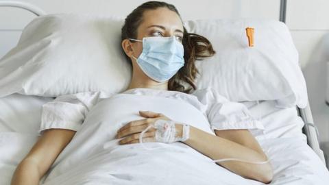 A stock image of a woman in a hospital bed