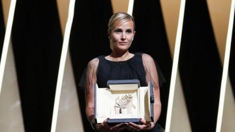 Director Julia Ducournau posing with the award on stage