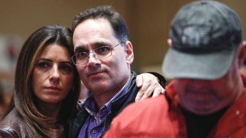 Two people hold each other at the Republican Stronger Nevada PAC's watch party in Las Vegas, while a third man looks down