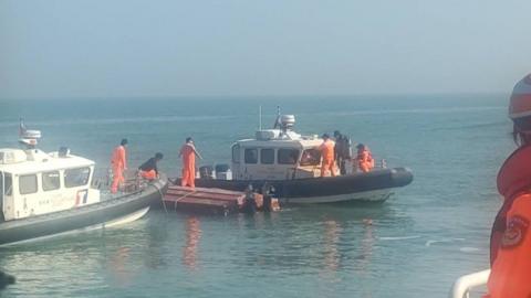 Taiwanese coast guards inspect the vessel that capsized during a chase off the coast of Kinmen
