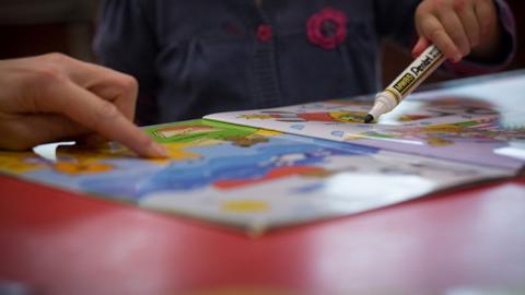 A young girl draws at a playgroup for pre-school aged children
